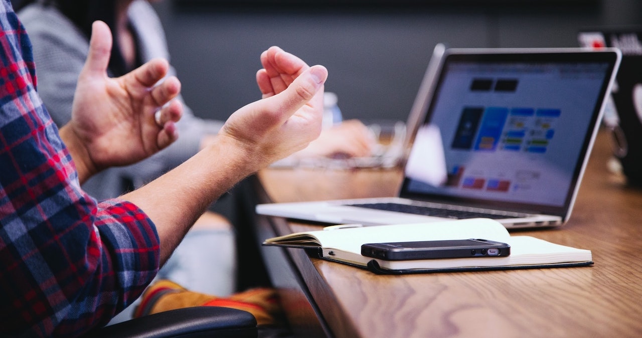 A meeting room at work with a laptop on the desk as people discuss top communications tips