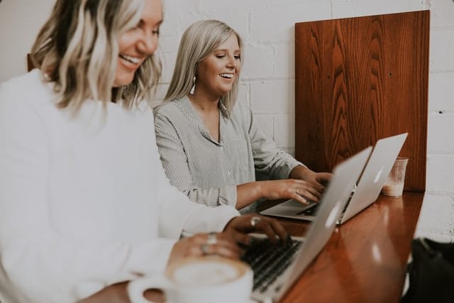 Two employees sat next to each other smiling and looking happy