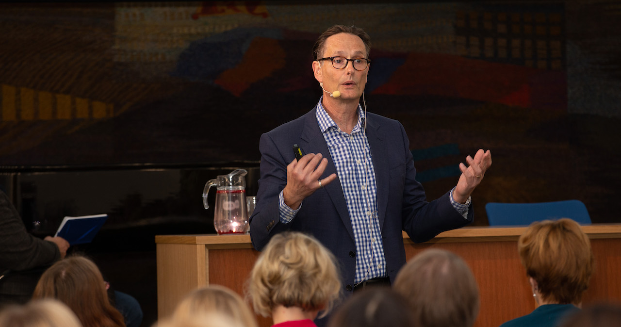 Liam FitzPatrick standing in front of an audience delivering a talk