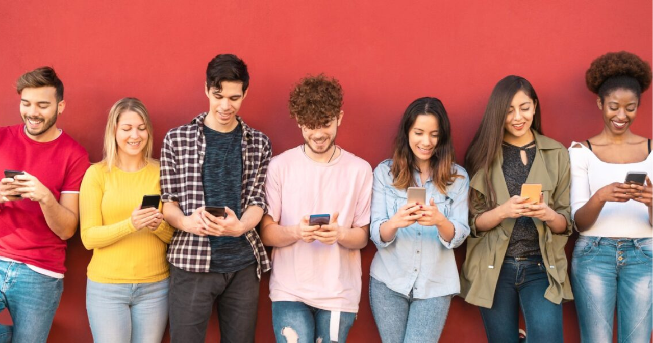 group of young people against a wall on their smart phones