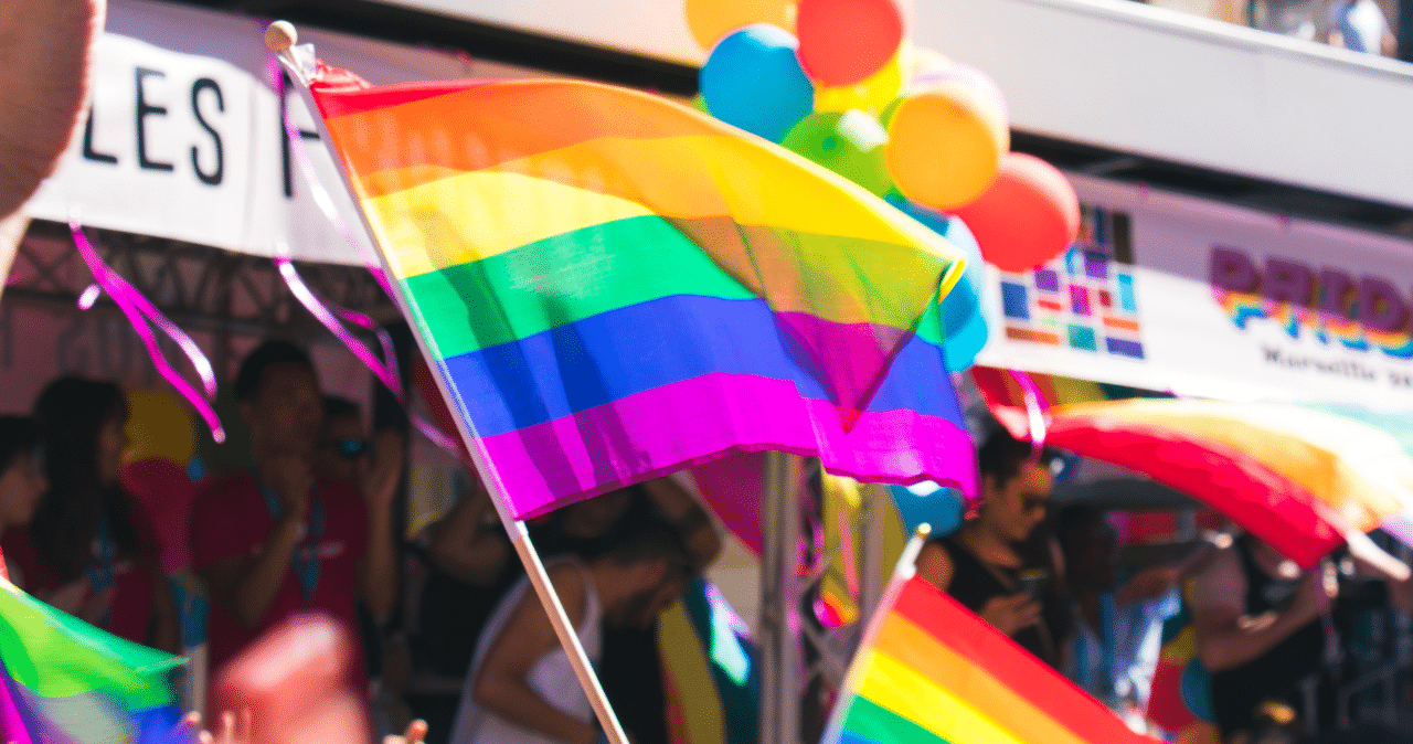 pride flag being waved at a pride parade with other people around