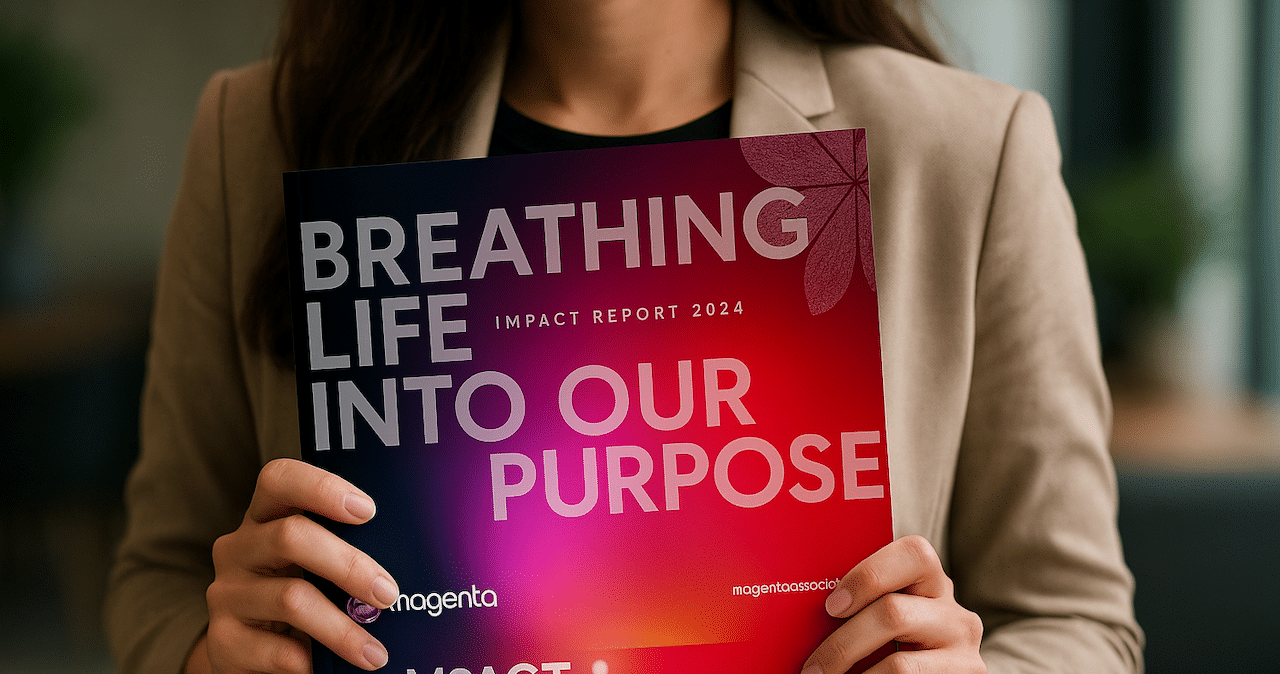 A woman holding a copy of Magenta's Impact Report so the front cover faces the audience