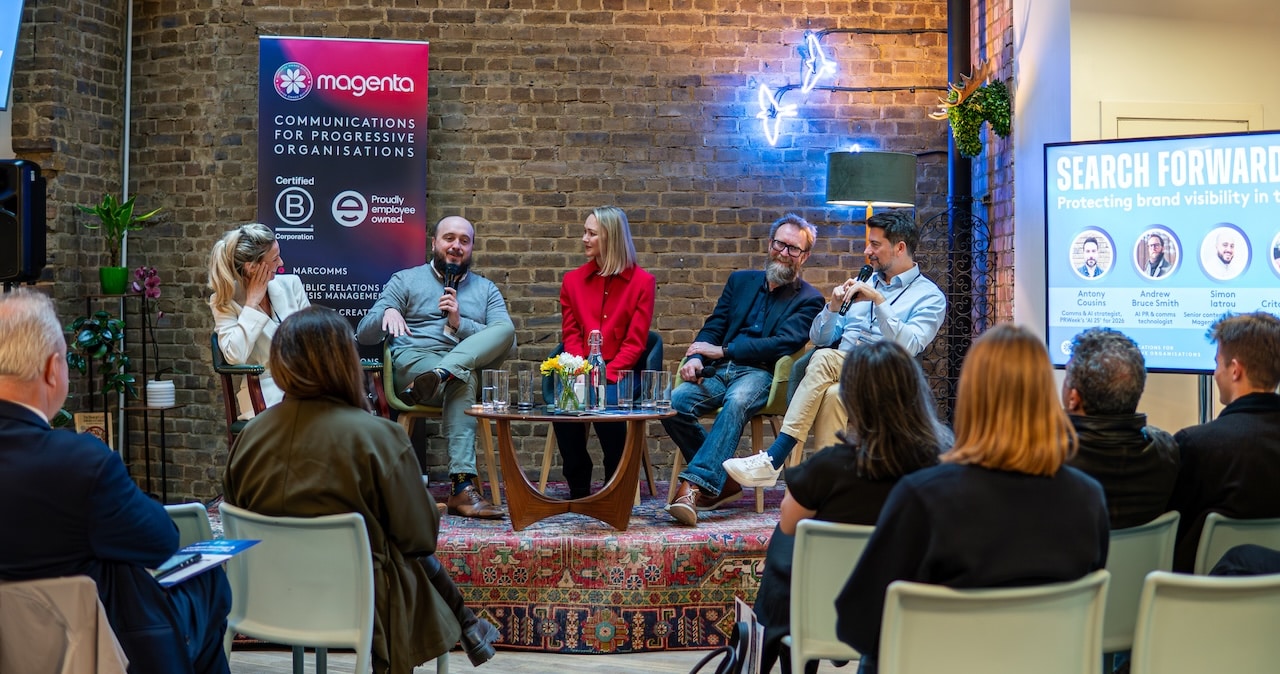 Five people (the panellists for the Search Forward event) sit on stage in front of an audience