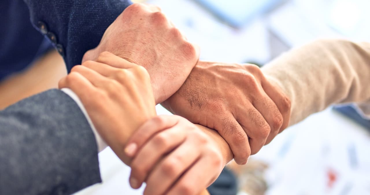 Four people holding each other's wrists, creating an interlinkedchain