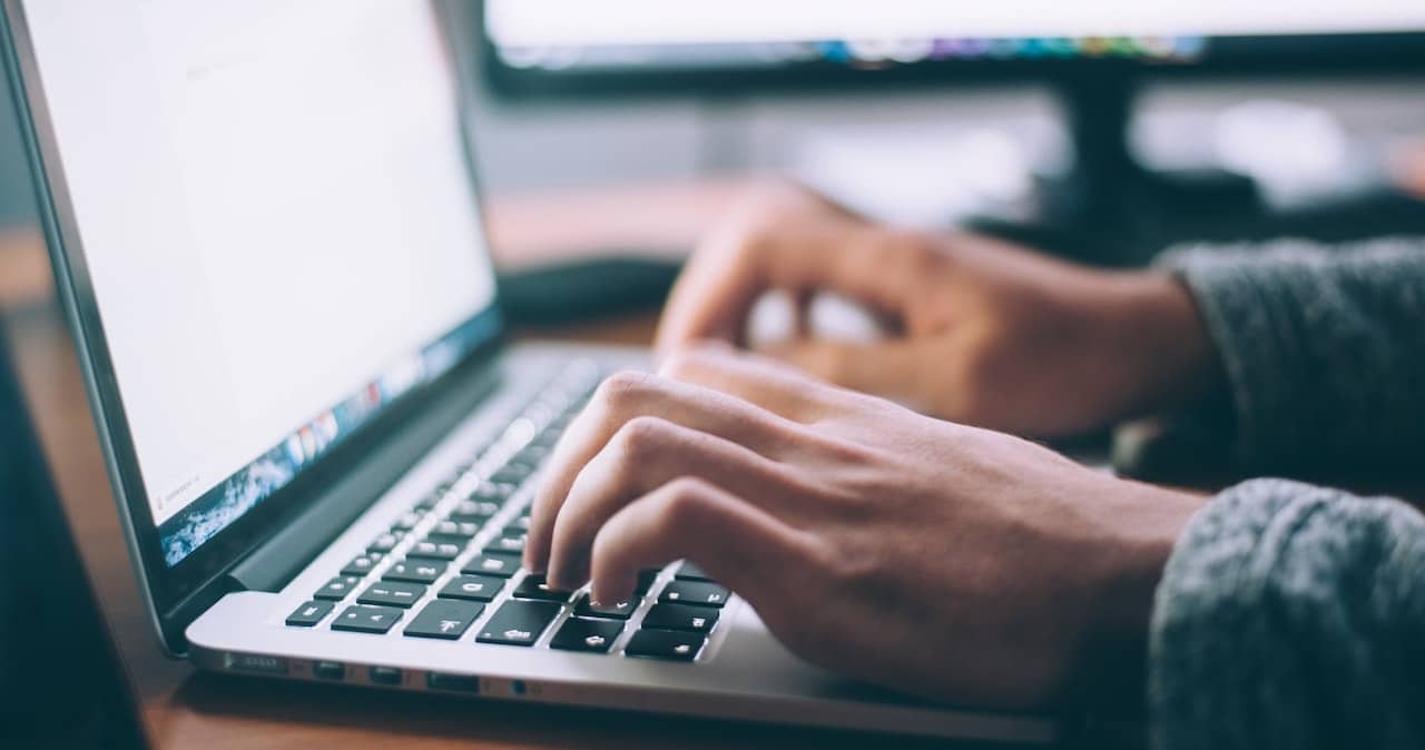 A person typing content on a laptop