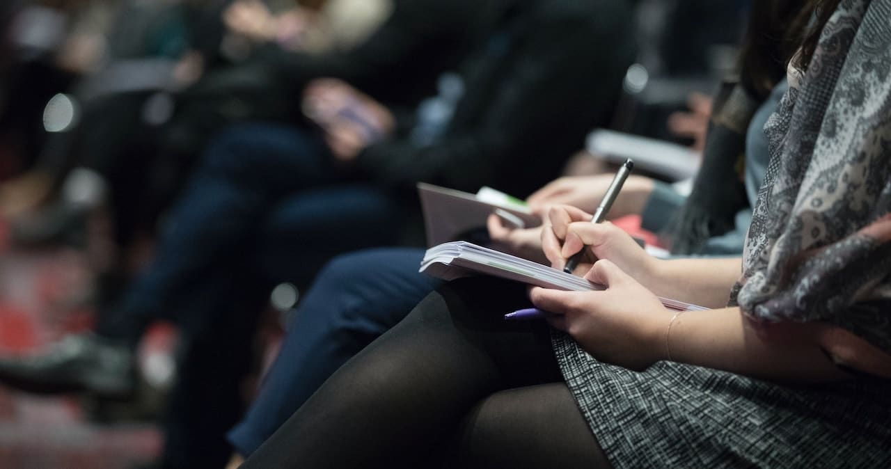A journalist taking notes at a press conference