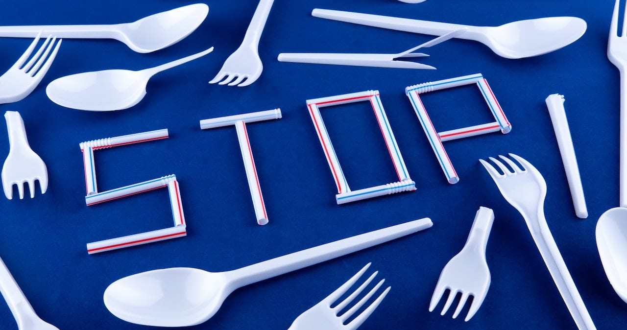 Plastic straws speel the word 'Stop' surrounded by plastic cutlery