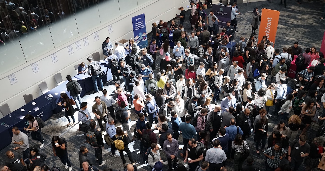 A crowd looks at stands in a busy conference venue