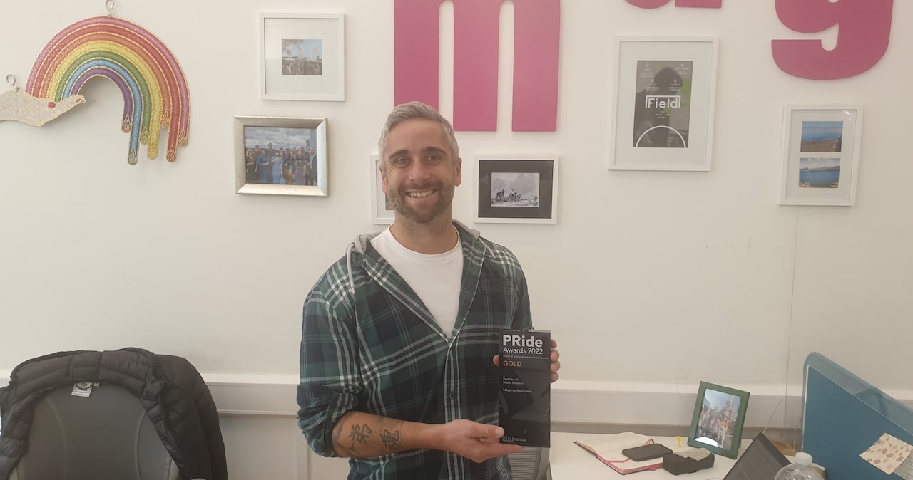 Craig Peters, consultant at Magenta Associates, standing in front of a wall holding the GOLD CIPR PRide award for Best Use of Media Relations