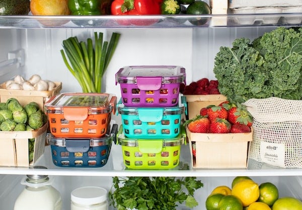 Boxes of food and fresh vegetables stacked in a fridge