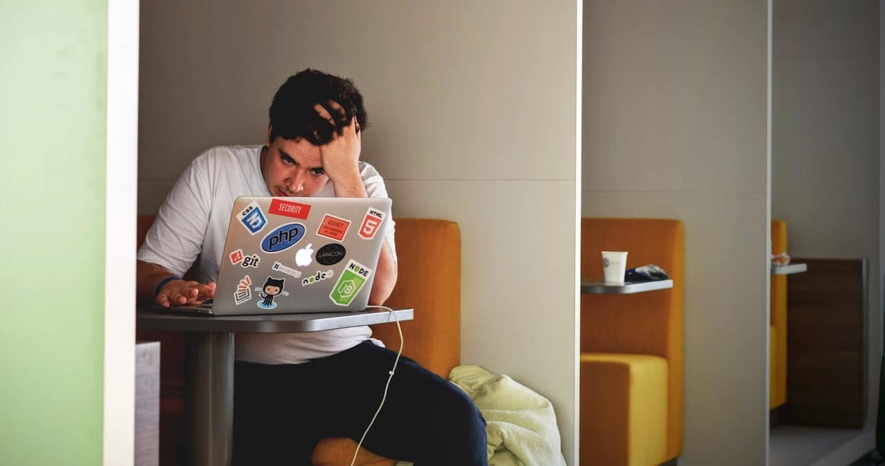 A man using a laptop at work and looking stressed