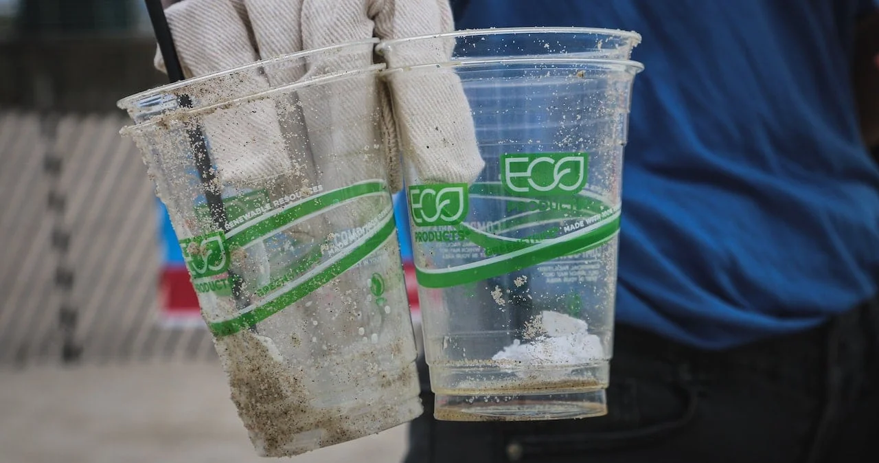 A person holding two plastic cups made from recycled material