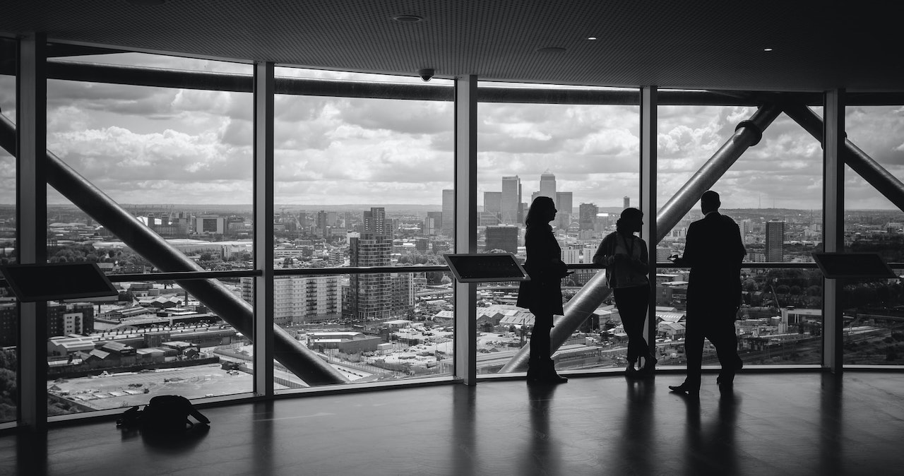 Three people standing in an empty office in a large building