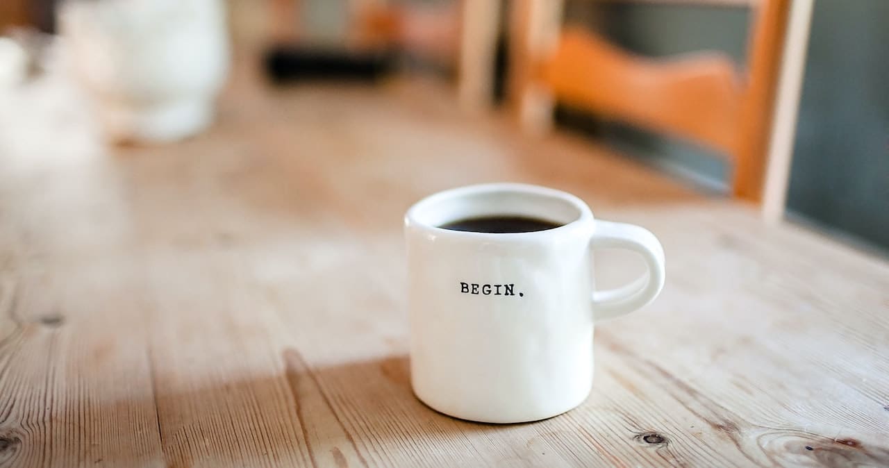 A coffee cup on a table with the word 'begin' on the side