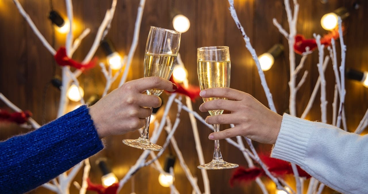 Two people clink champagne glasses at an office Christmas party