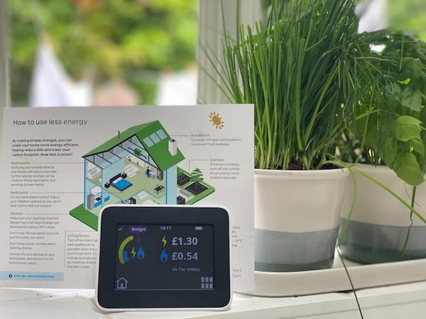 A smart meter standing in front of a booklet about how to reduce energy use