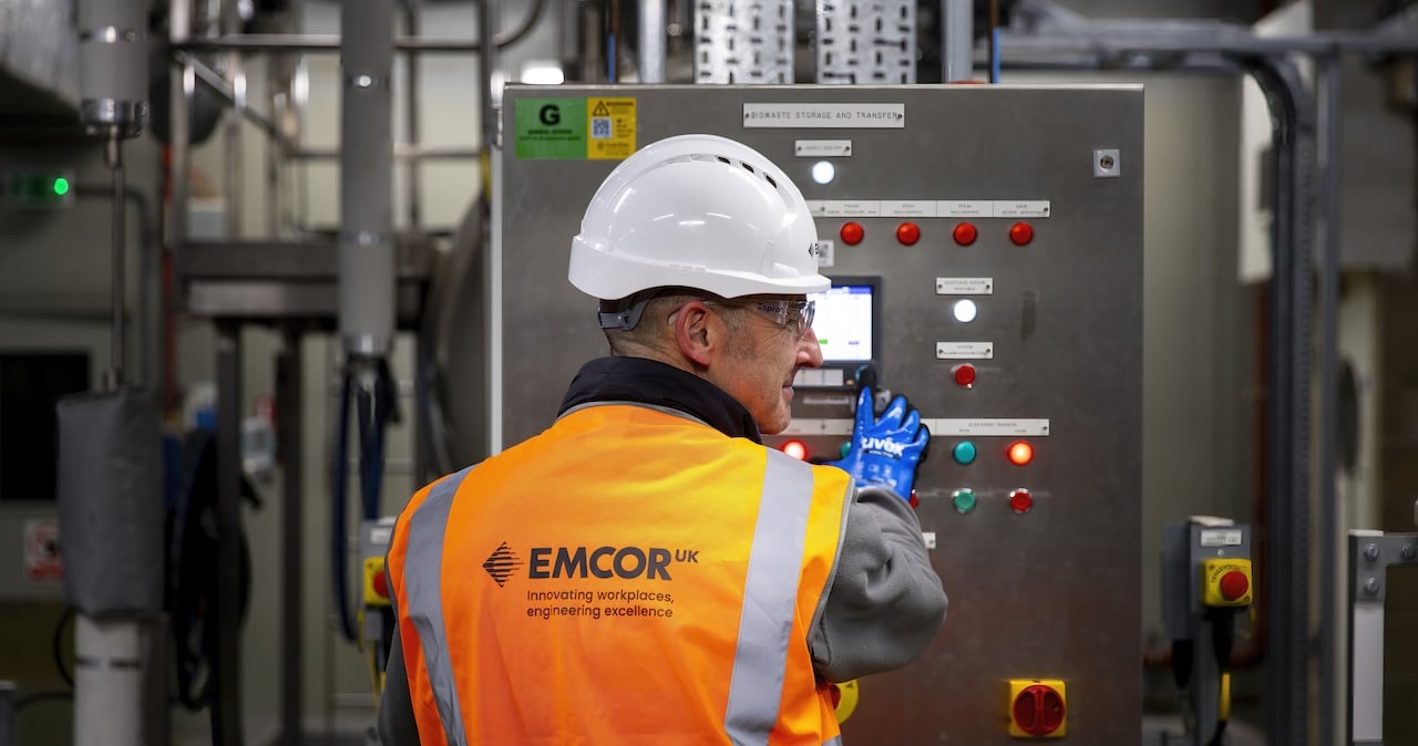 An EMCOR UK engineer standing in front on a power unit
